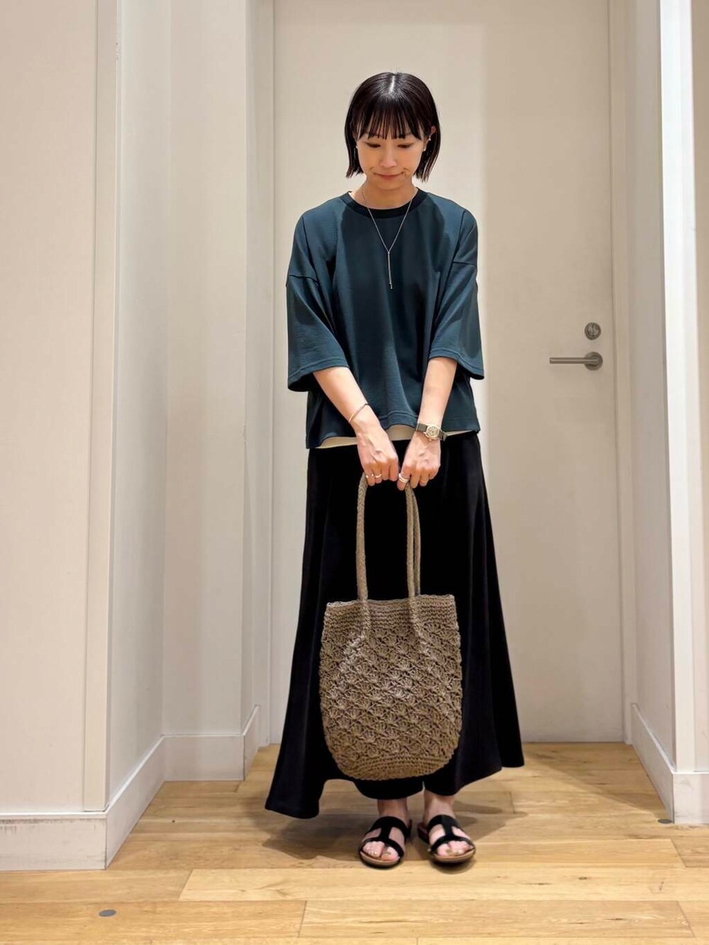 グレー系のトートバッグ、ホワイト系のタンクトップ、ブラック系のスカートを着用したレディースの夏コーディネートの3枚目の写真