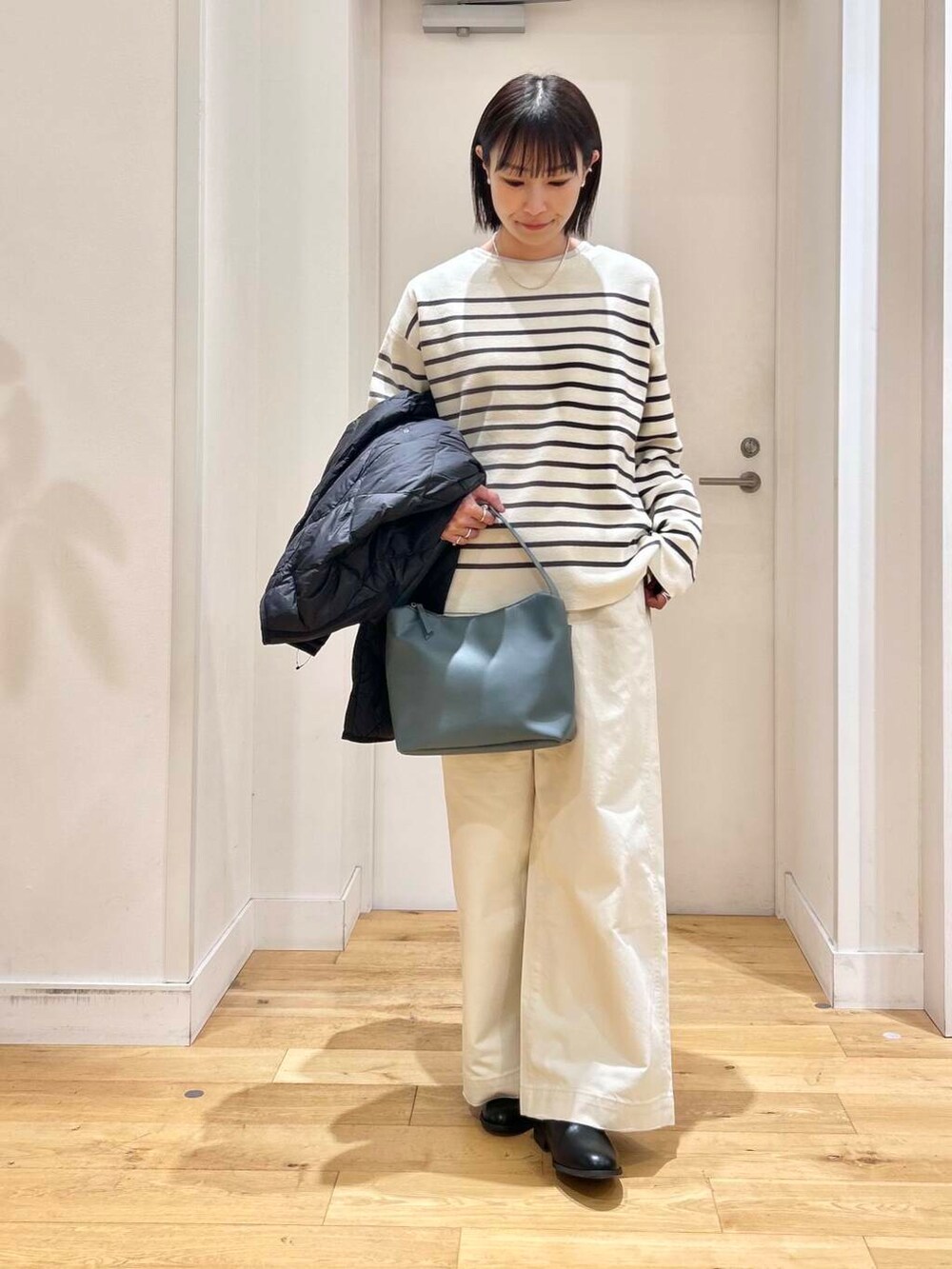 ブラック系のダウンジャケット/コート、ブルー系のショルダーバッグ、ブラック系のブーツを着用したレディースの冬コーディネートの8枚目の写真