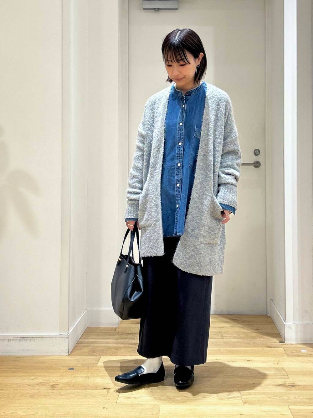 ブラック系のローファー、ブラック系のショルダーバッグ、ブルー系のスカートを着用したレディースの秋コーディネートの3枚目の写真