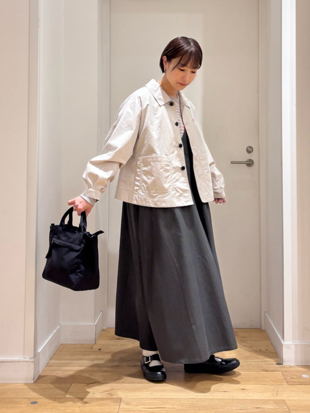 レッド系のスウェット、ベージュ系のテーラードジャケット、グリーン系のワンピースを着用したレディースの春コーディネートの5枚目の写真