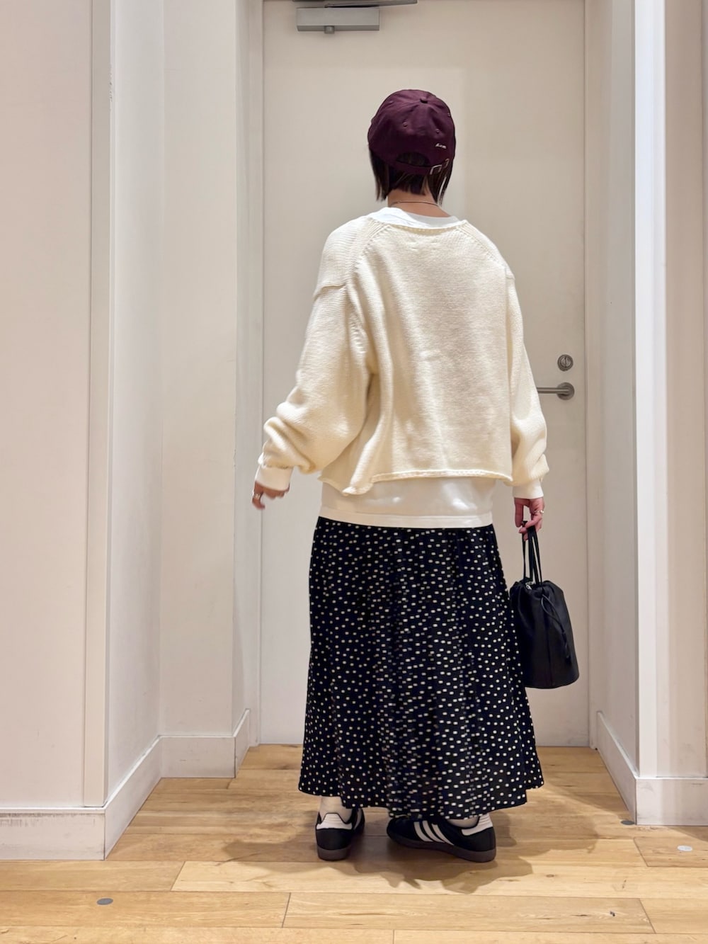 ホワイト系のカーディガン/ボレロ、ブラック系のバッグ、ブラック系のスカートを着用したレディースの冬コーディネートの6枚目の写真