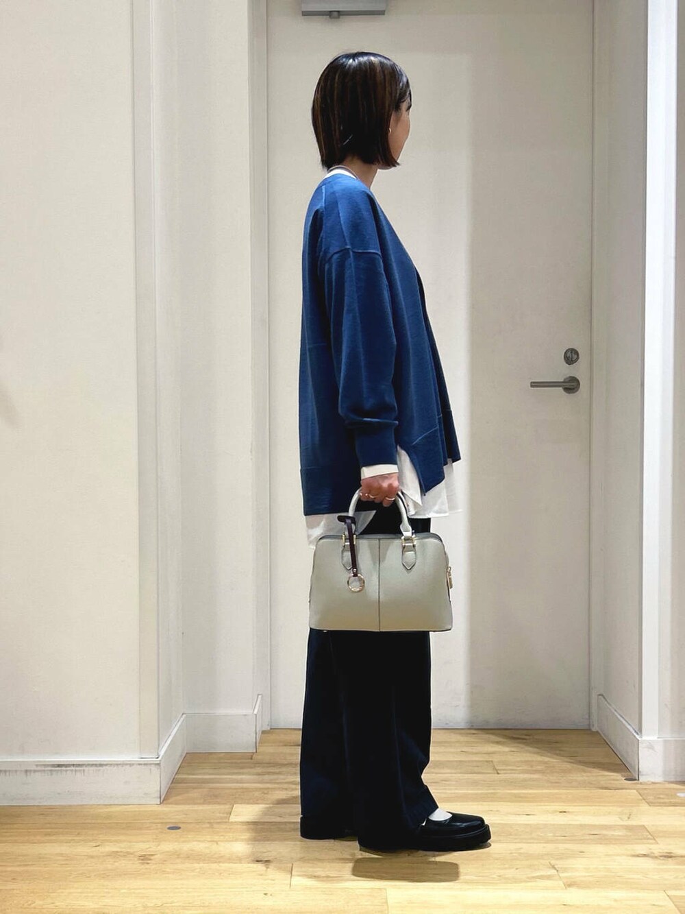 ブルー系のカーディガン/ボレロ、ホワイト系のシャツ/ブラウス、グレー系のハンドバッグを着用したレディースの秋コーディネートの5枚目の写真
