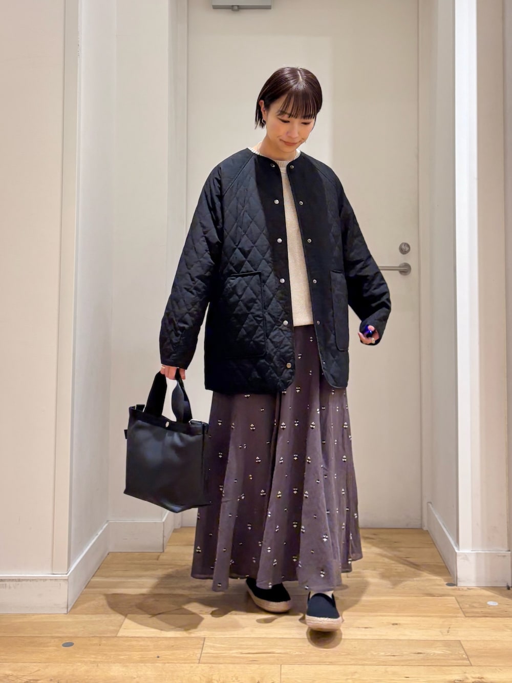 ブラック系のハンドバッグ、グレー系のニット/セーター、グレー系のスカートを着用したレディースの春コーディネートの5枚目の写真