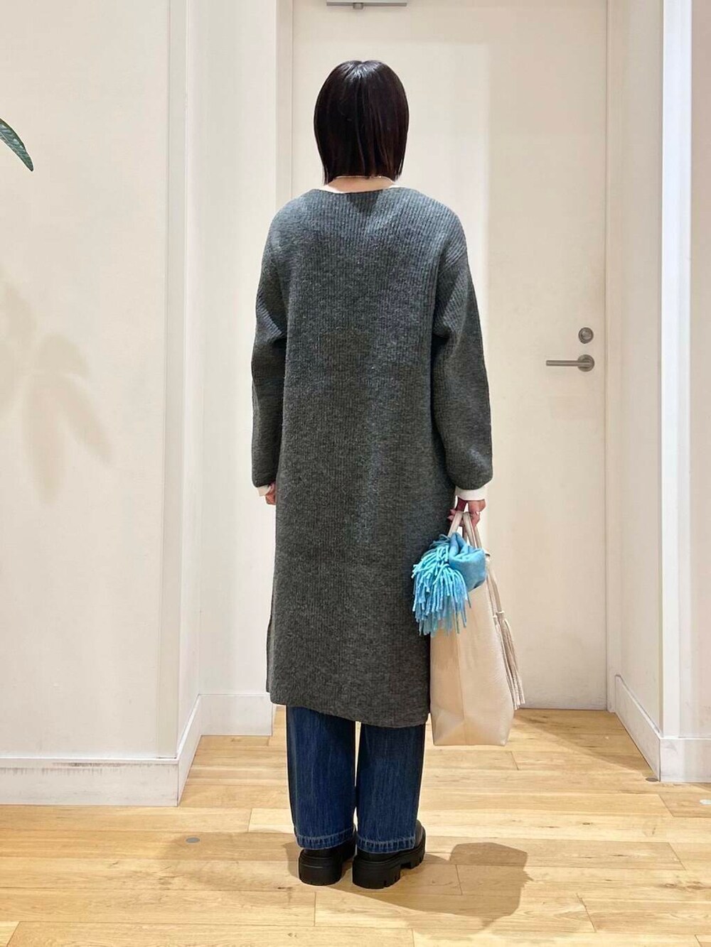 ホワイト系のトートバッグ、ブルー系のデニムパンツ、ブラック系のブーツを着用したレディースの冬コーディネートの6枚目の写真