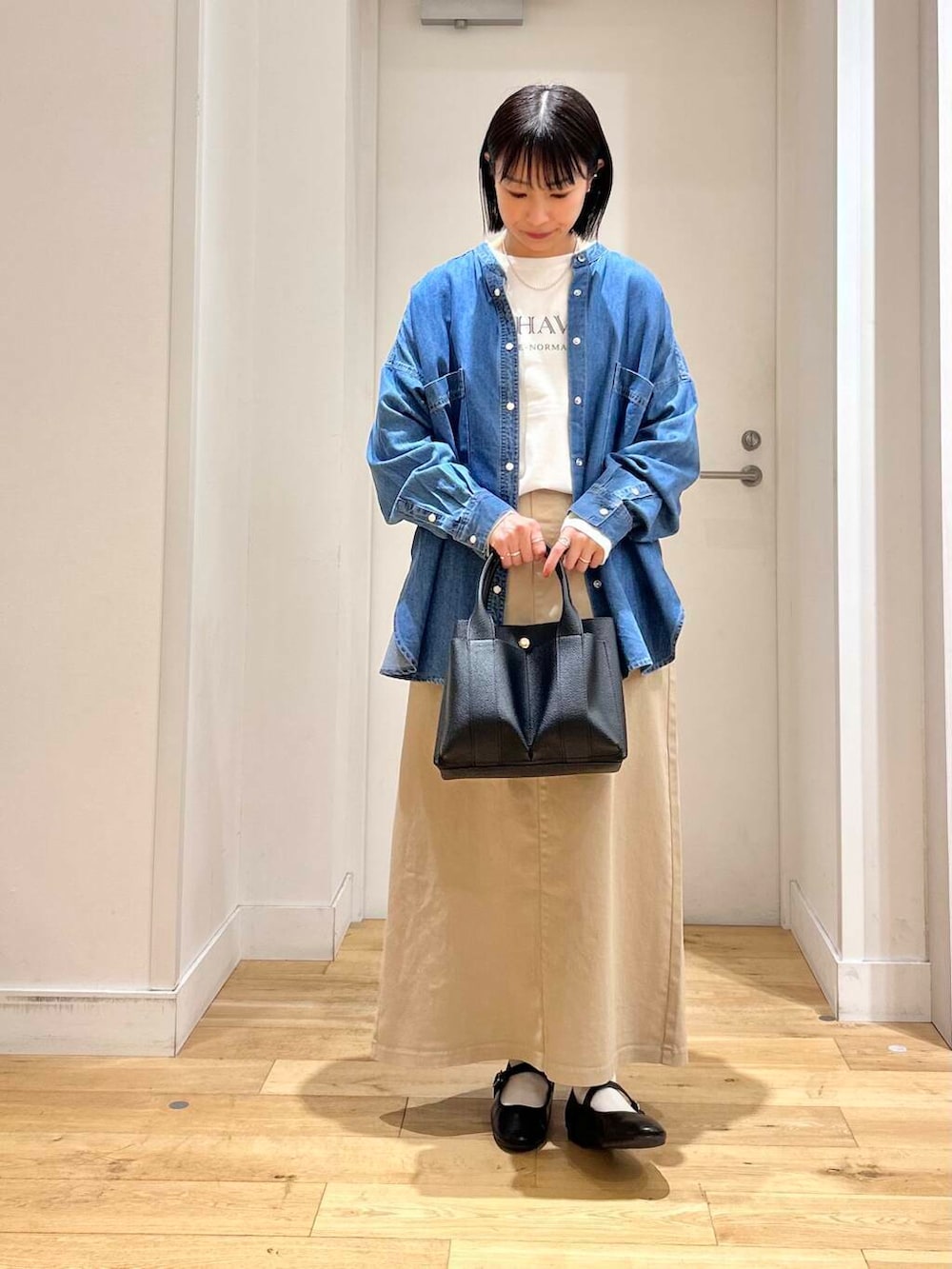 ブラック系のトートバッグ、ブルー系のシャツ/ブラウス、ブラック系のパンプスを着用したレディースの春コーディネートの2枚目の写真