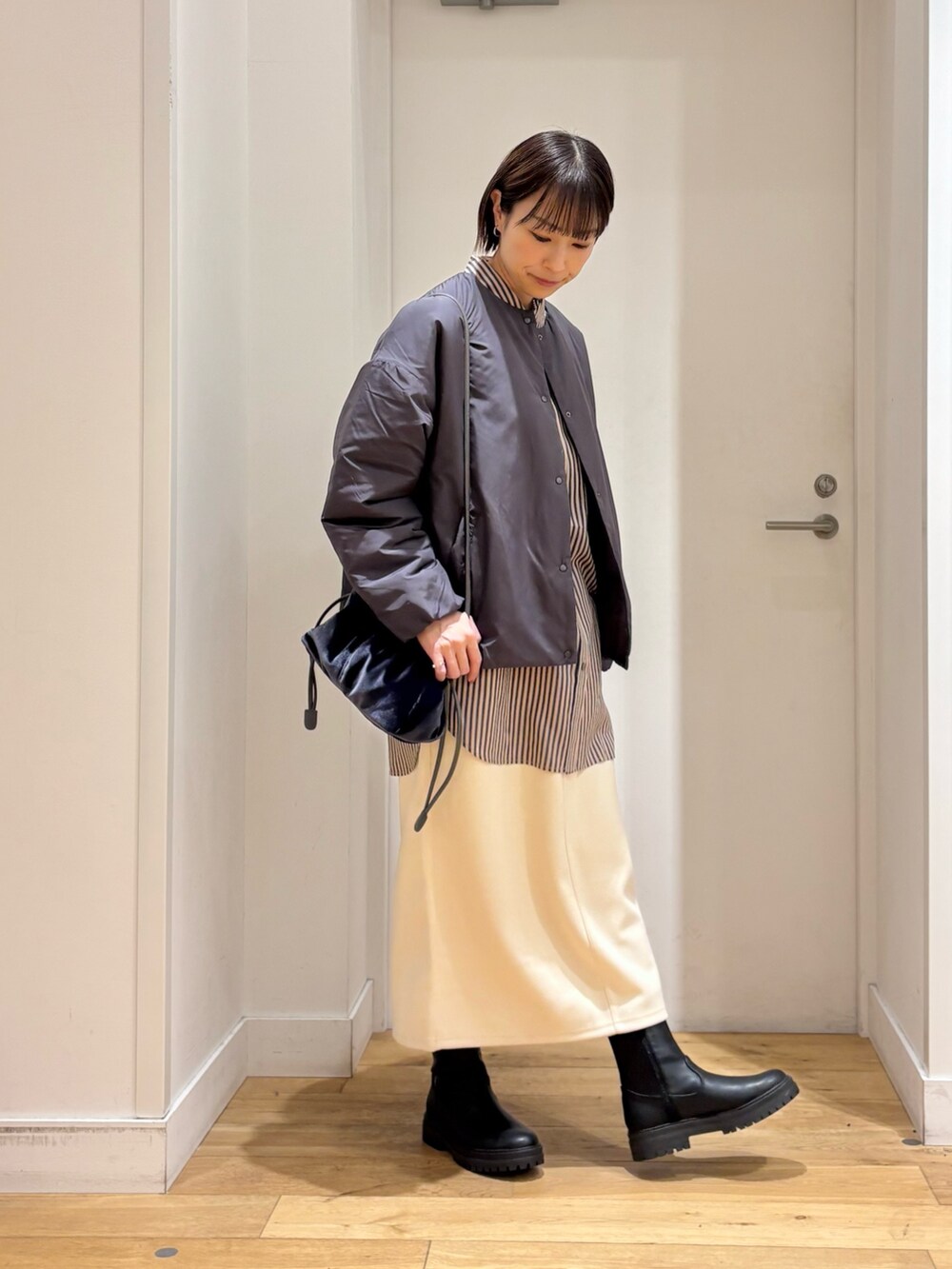 グレー系のブルゾン、グレー系のシャツ/ブラウス、ホワイト系のスカートを着用したレディースの冬コーディネートの3枚目の写真