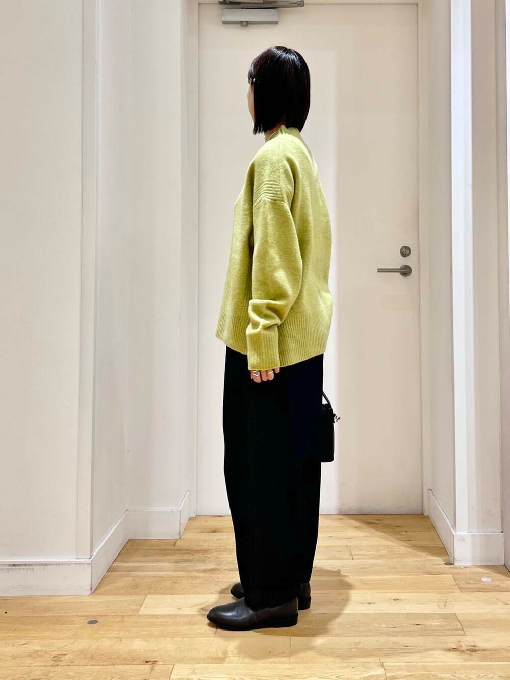 グレー系のブーツ、グリーン系のニット/セーター、ブルー系のデニムパンツを着用したレディースの冬コーディネートの4枚目の写真