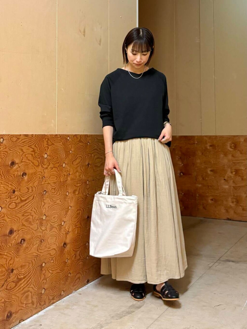 ブラック系のサンダル、ベージュ系のスカート、ブラック系のTシャツ/カットソーを着用したレディースの春コーディネートの2枚目の写真