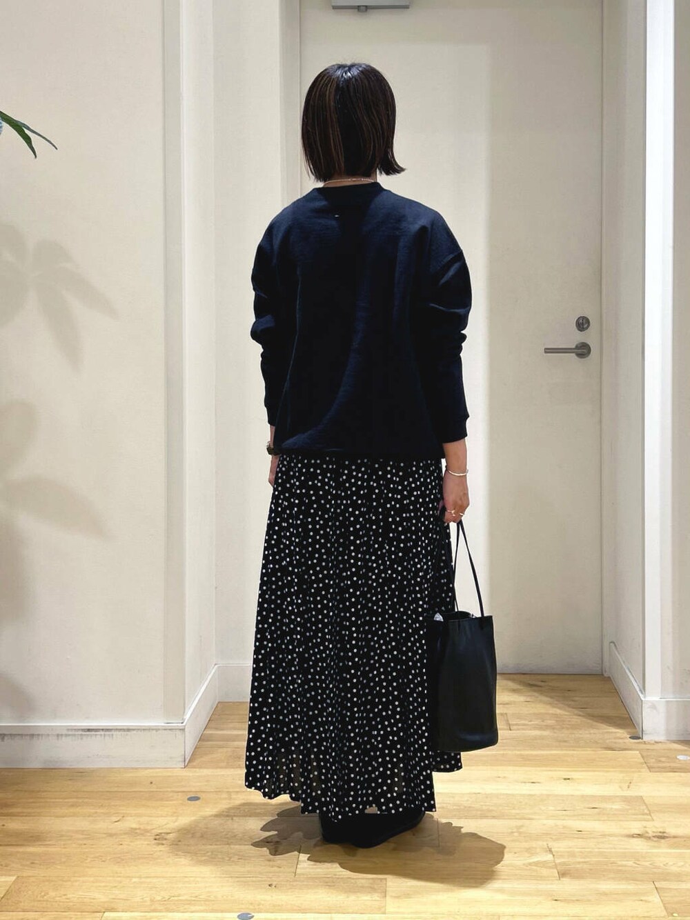 ブラック系のスニーカー、ブラック系のショルダーバッグ、ブラック系のスカートを着用したレディースの秋コーディネートの5枚目の写真