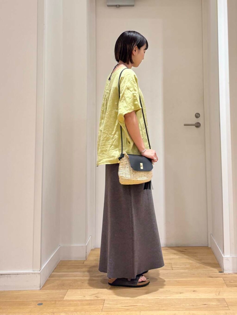 ベージュ系のショルダーバッグ、グレー系のスカート、グレー系のサンダルを着用したレディースの夏コーディネートの4枚目の写真