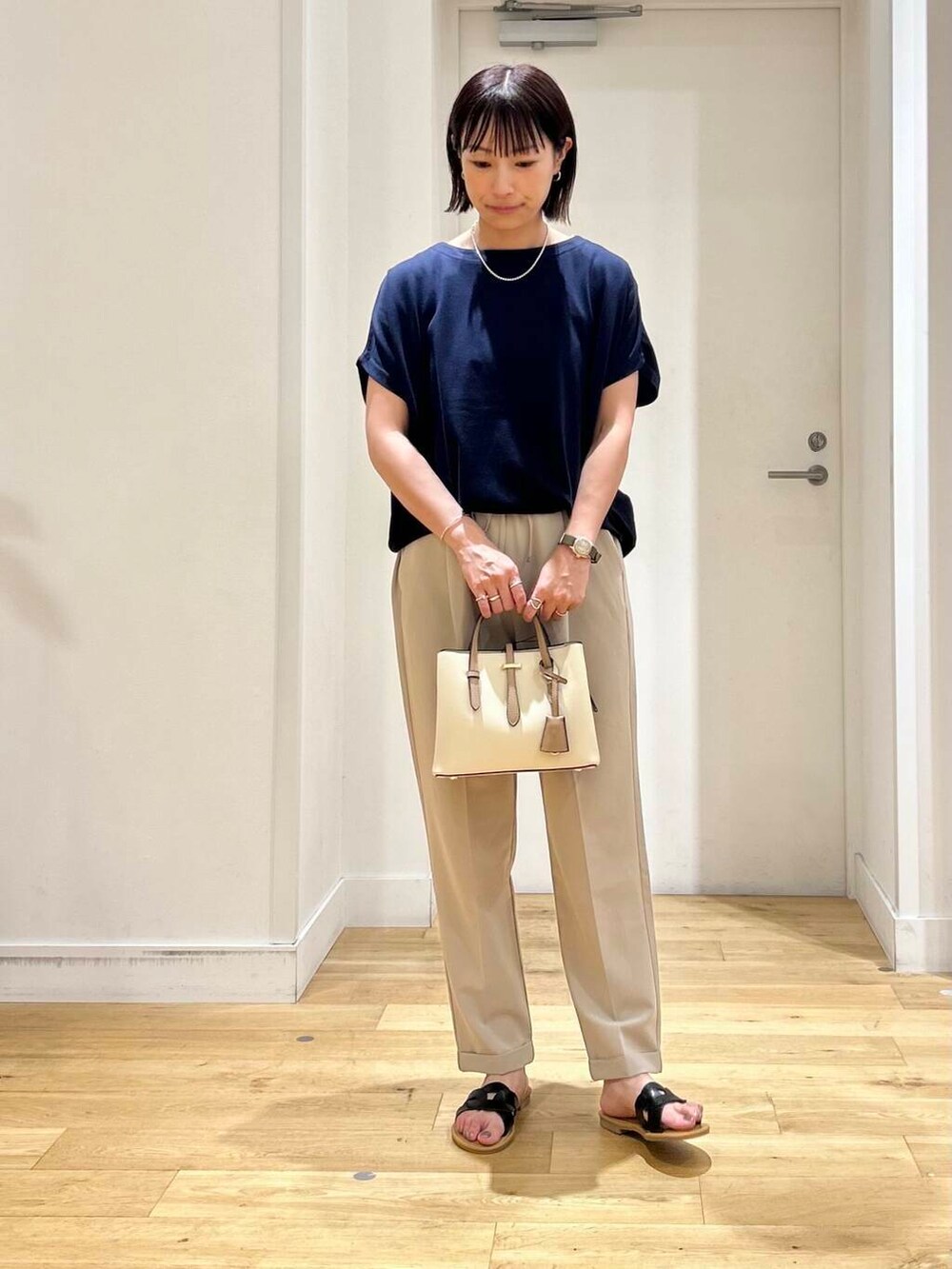 ホワイト系のハンドバッグ、ベージュ系のその他パンツ、ブラック系のサンダルを着用したレディースの夏コーディネートの3枚目の写真