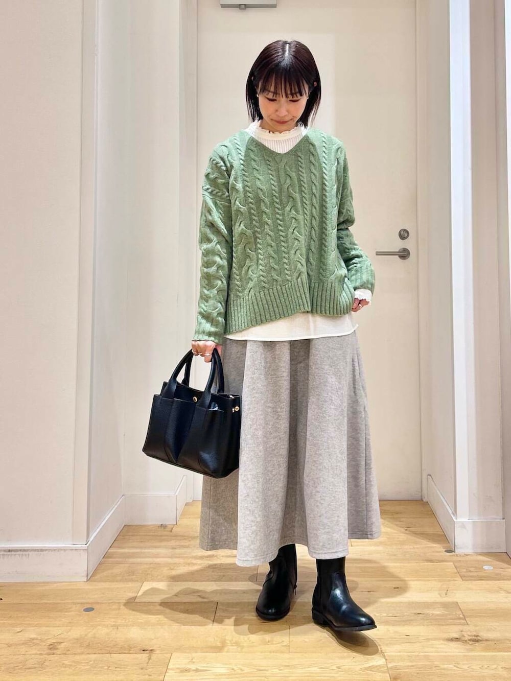 グリーン系のニット/セーター、ホワイト系のシャツ/ブラウス、ブラック系のブーツを着用したレディースの冬コーディネートの3枚目の写真