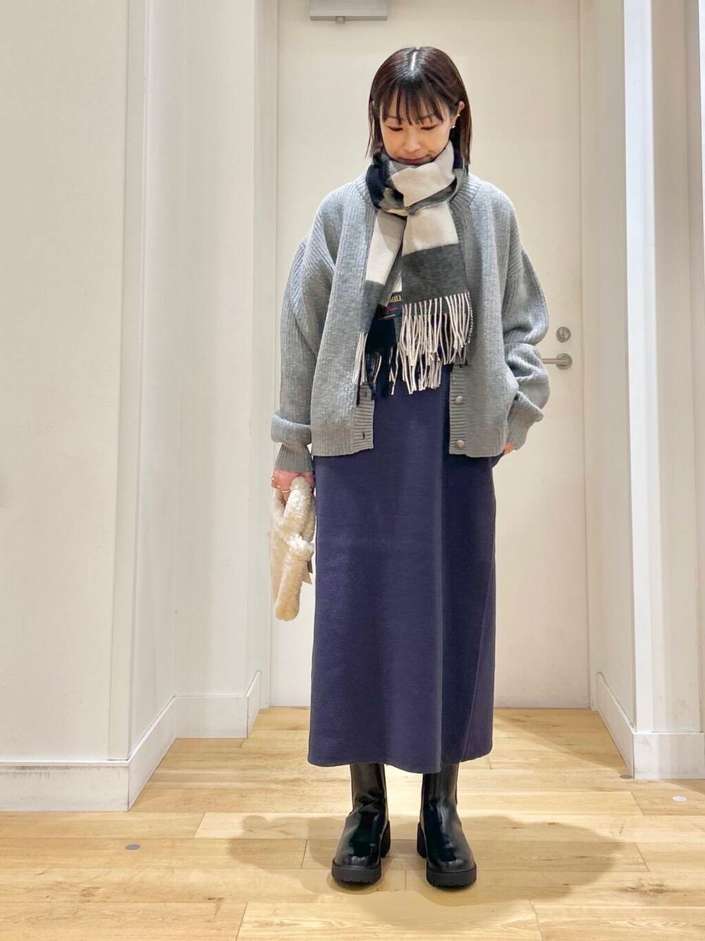 グレー系のカーディガン/ボレロ、ブラック系のブーツ、ベージュ系のハンドバッグを着用したレディースの冬コーディネートの2枚目の写真