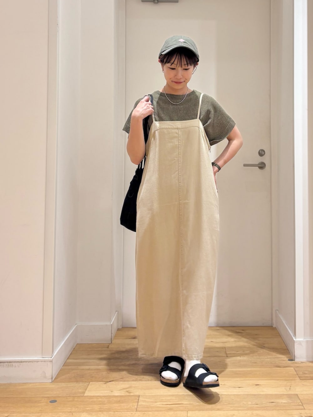 ベージュ系のワンピース、グリーン系のニット/セーター、ブラック系のサンダルを着用したレディースの夏コーディネートの2枚目の写真