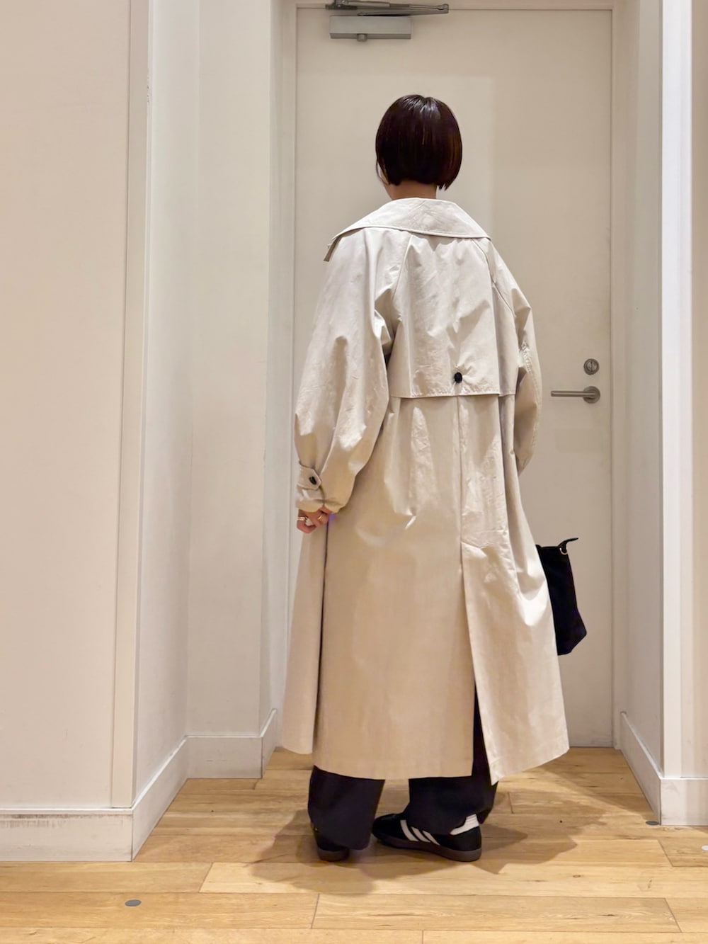 ブルー系のニット/セーター、ホワイト系のTシャツ/カットソー、ベージュ系のトレンチコートを着用したレディースの春コーディネートの6枚目の写真