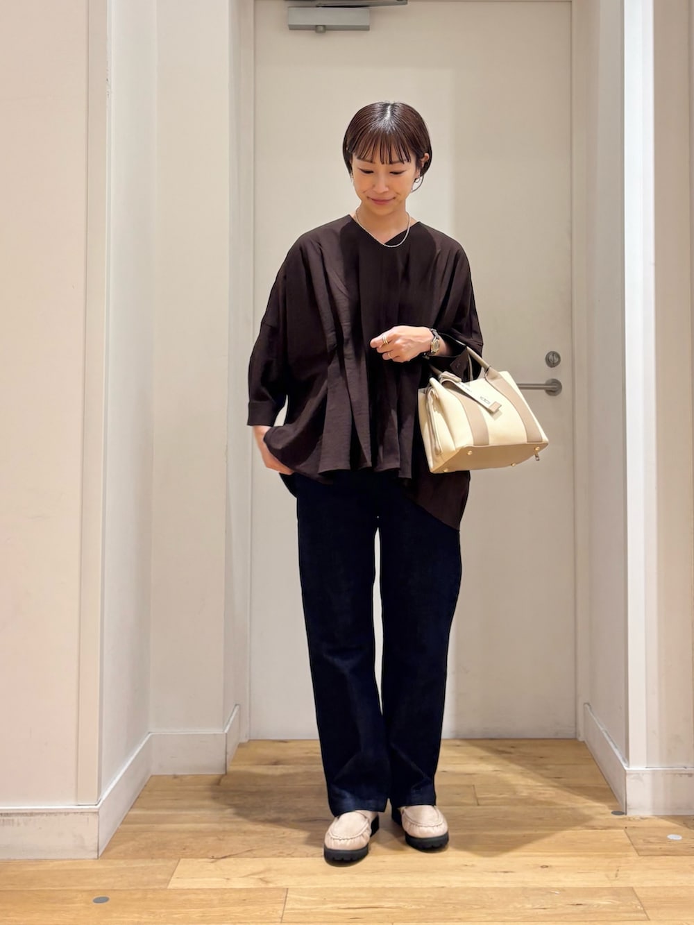 ブラウン系のシャツ/ブラウス、ブルー系のデニムパンツ、ホワイト系のハンドバッグを着用したレディースの秋コーディネートの2枚目の写真
