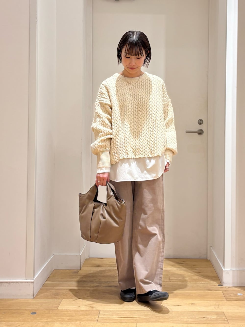 ブラック系のダウンジャケット/コート、ベージュ系のニット/セーター、ホワイト系のシャツ/ブラウスを着用したレディースの冬コーディネートの6枚目の写真