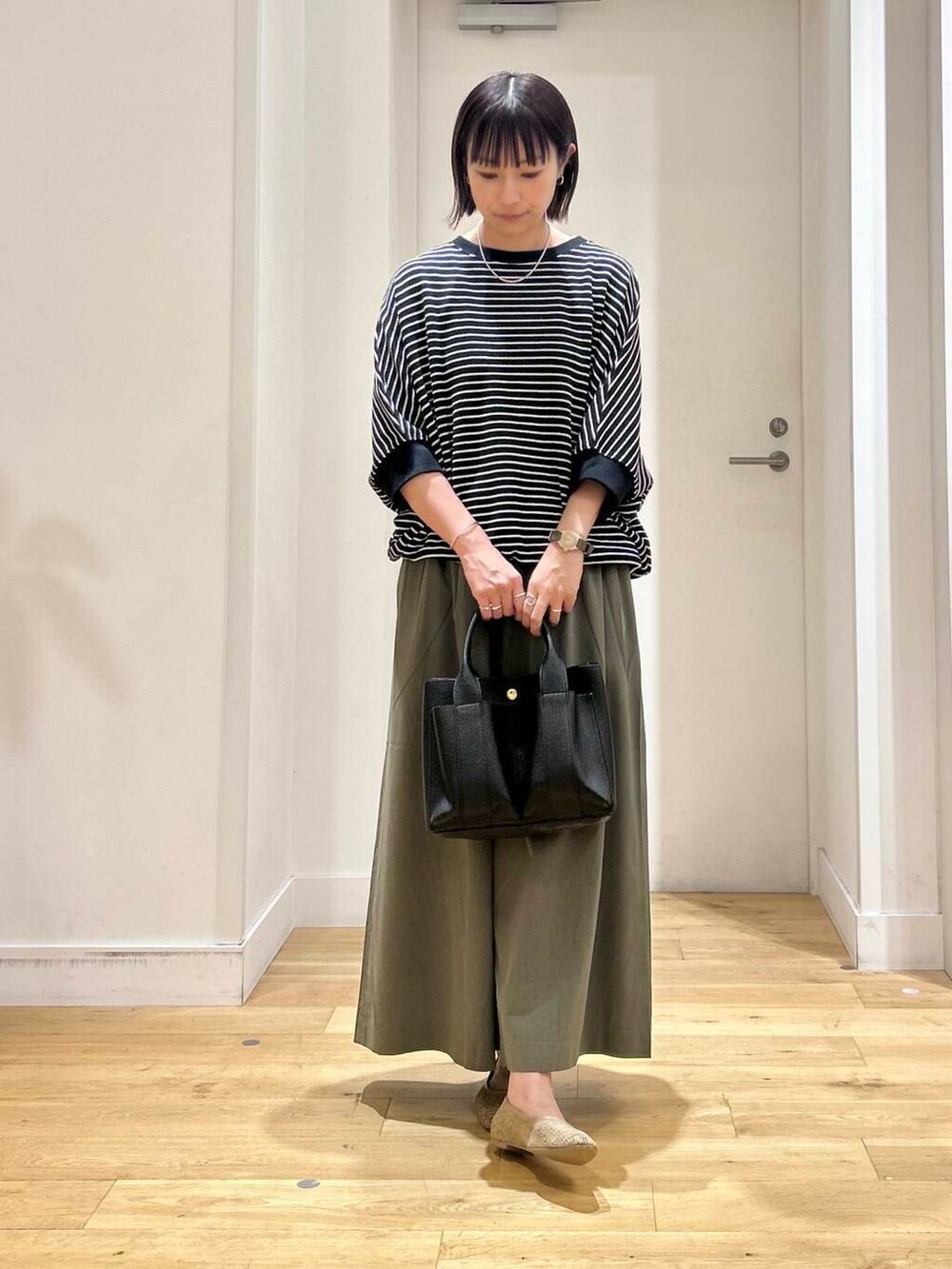 ブラック系のトートバッグ、グリーン系のその他パンツ、ベージュ系のパンプスを着用したレディースの夏コーディネートの2枚目の写真