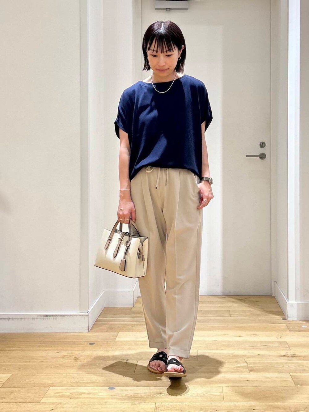 ホワイト系のハンドバッグ、ベージュ系のその他パンツ、ブラック系のサンダルを着用したレディースの夏コーディネートの4枚目の写真