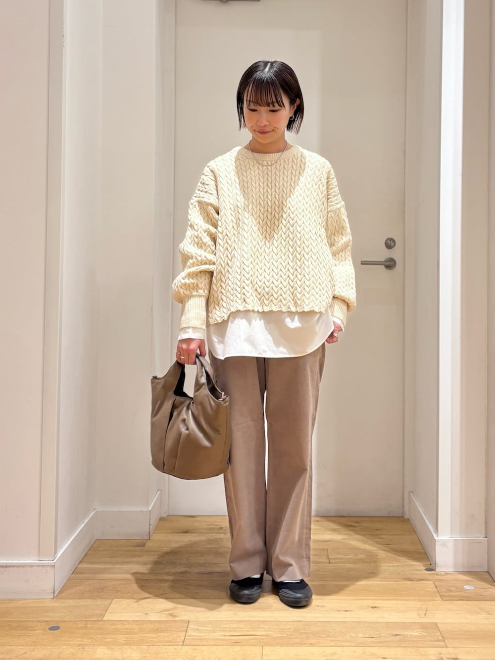 ブラック系のダウンジャケット/コート、ベージュ系のニット/セーター、ホワイト系のシャツ/ブラウスを着用したレディースの冬コーディネートの5枚目の写真