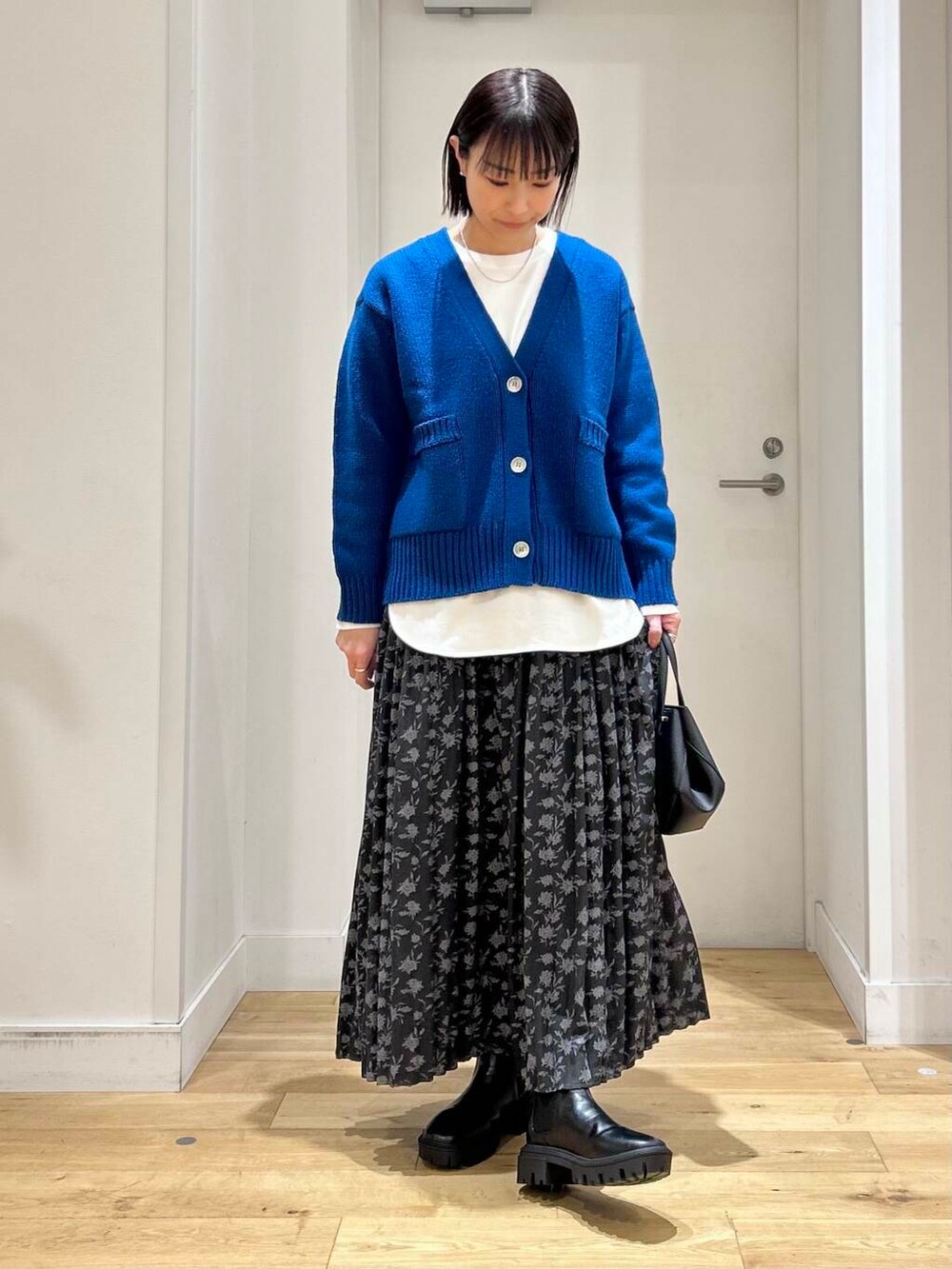 ブラック系のショルダーバッグ、ブラック系のブーツ、ブルー系のカーディガン/ボレロを着用したレディースの冬コーディネートの3枚目の写真