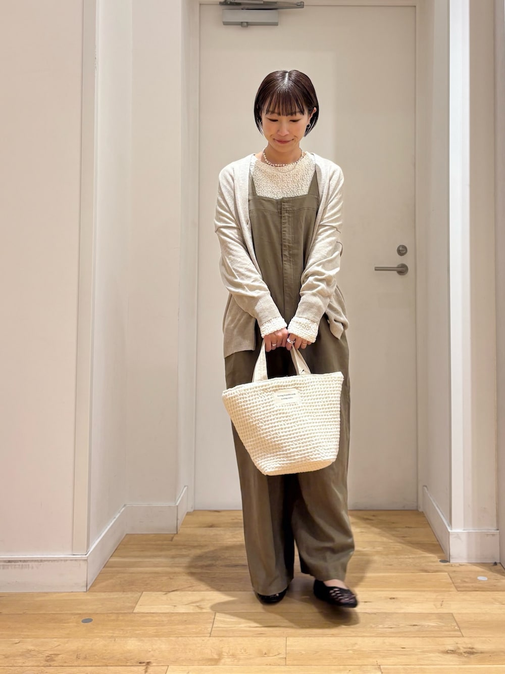 ホワイト系のTシャツ/カットソー、ベージュ系のカーディガン/ボレロ、グリーン系のサロペット/オーバーオールを着用したレディースの春コーディネートの2枚目の写真