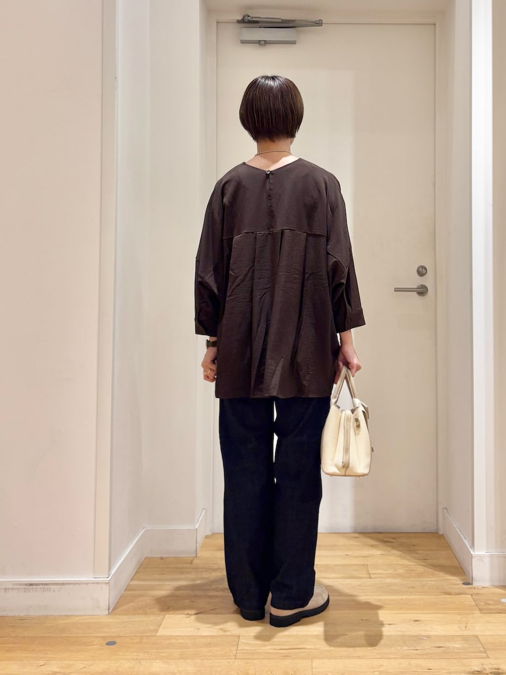 ブラウン系のシャツ/ブラウス、ブルー系のデニムパンツ、ホワイト系のハンドバッグを着用したレディースの秋コーディネートの4枚目の写真