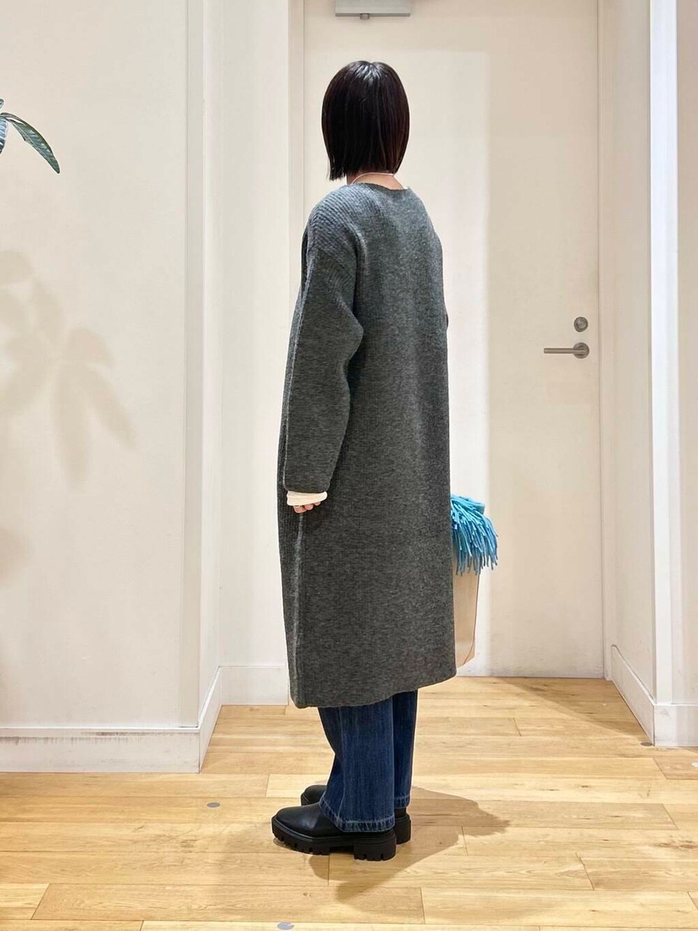 ホワイト系のトートバッグ、ブルー系のデニムパンツ、ブラック系のブーツを着用したレディースの冬コーディネートの5枚目の写真