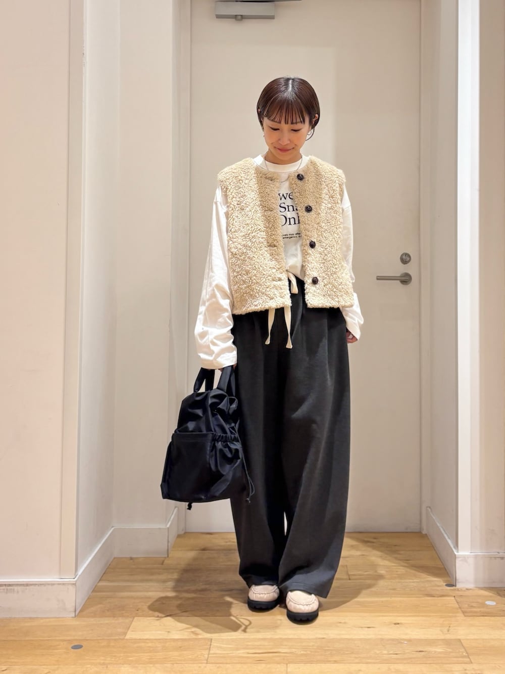 ベージュ系のダウンベスト、グレー系のその他パンツ、ホワイト系のTシャツ/カットソーを着用したレディースの秋コーディネートの2枚目の写真