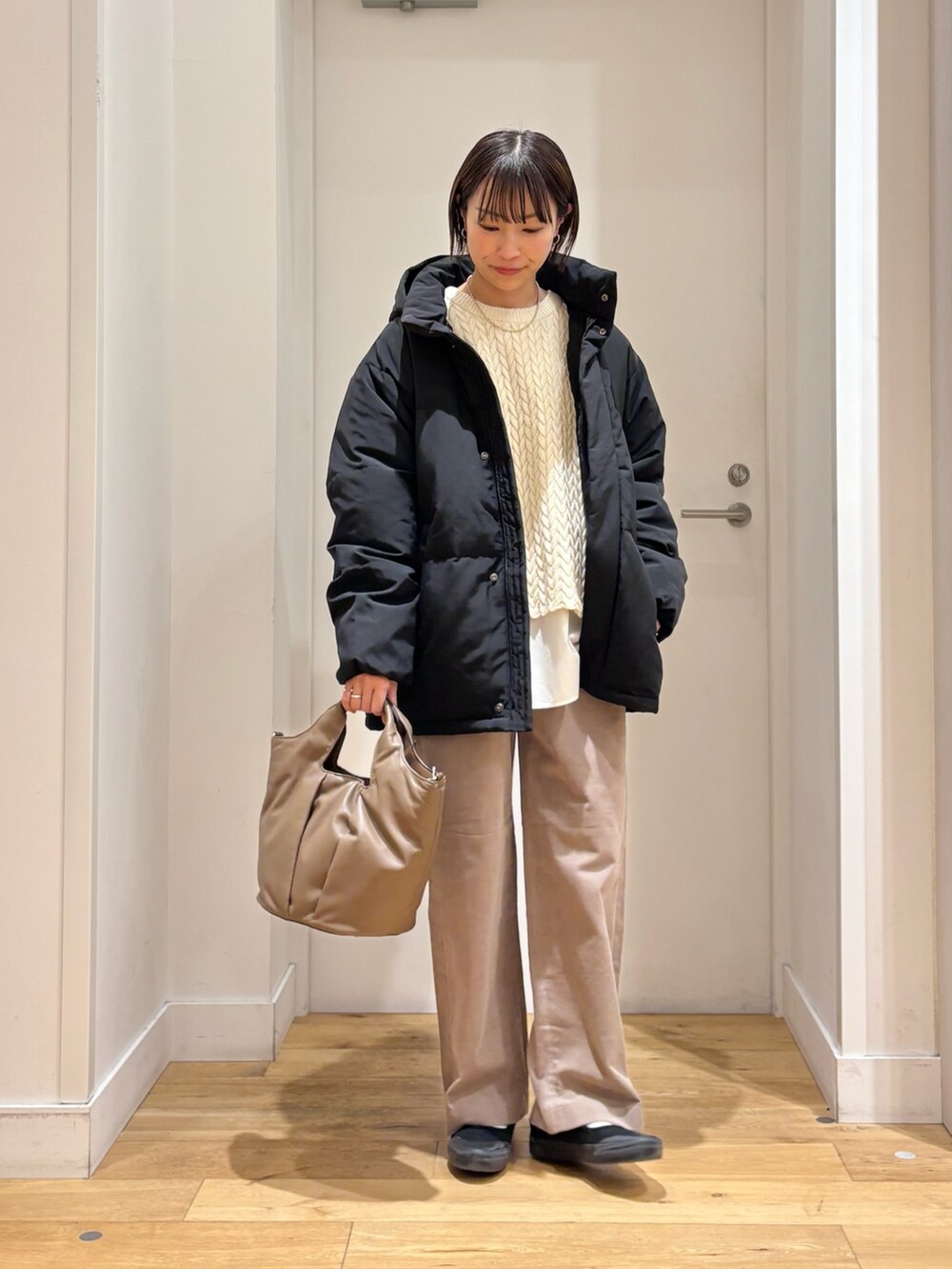 ブラック系のダウンジャケット/コート、ベージュ系のニット/セーター、ホワイト系のシャツ/ブラウスを着用したレディースの冬コーディネートの2枚目の写真