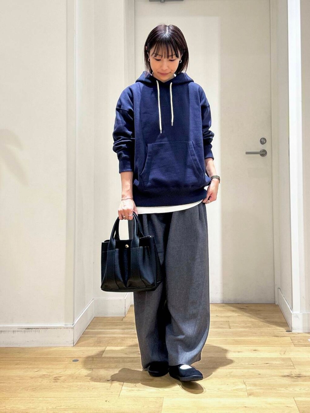 ブラック系のトートバッグ、ブラック系のバレエシューズ、ブルー系のパーカーを着用したレディースの秋コーディネートの3枚目の写真