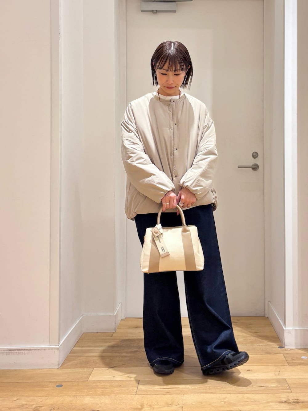 ベージュ系のブルゾン、ベージュ系のニット/セーター、ホワイト系のハンドバッグを着用したレディースの冬コーディネートの2枚目の写真