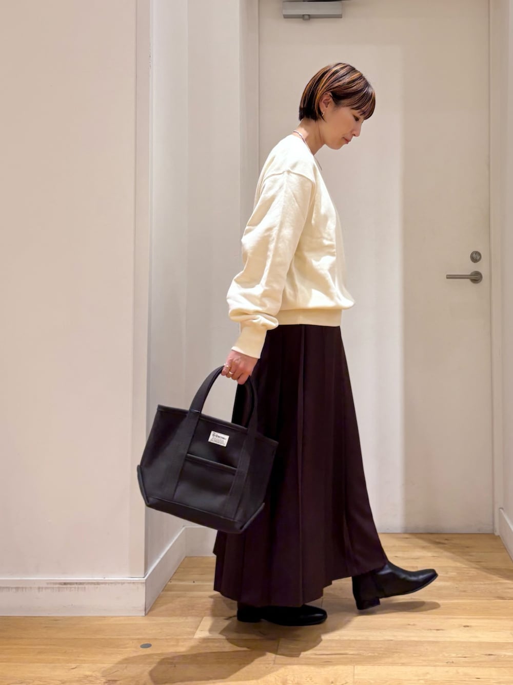 ホワイト系のスウェット、ブラウン系のスカート、グレー系のトートバッグを着用したレディースの秋コーディネートの4枚目の写真