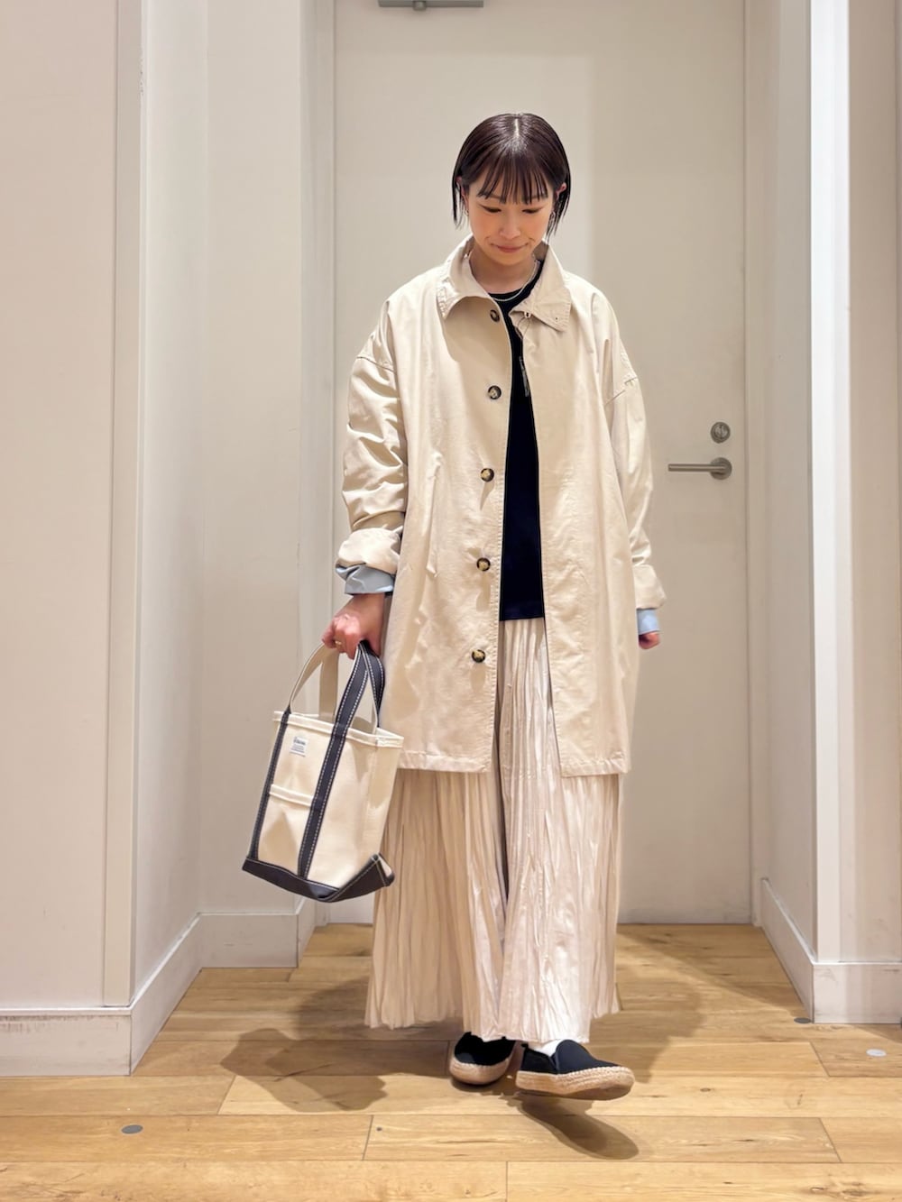 ホワイト系のTシャツ/カットソー、ベージュ系のステンカラーコート、ブルー系のベストを着用したレディースの春コーディネートの4枚目の写真