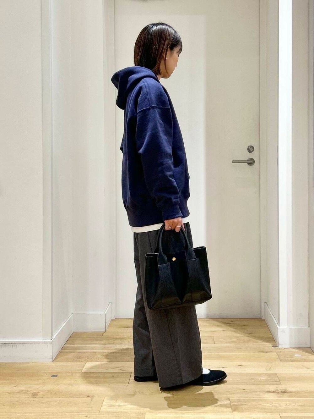 ブラック系のトートバッグ、ブラック系のバレエシューズ、ブルー系のパーカーを着用したレディースの秋コーディネートの4枚目の写真