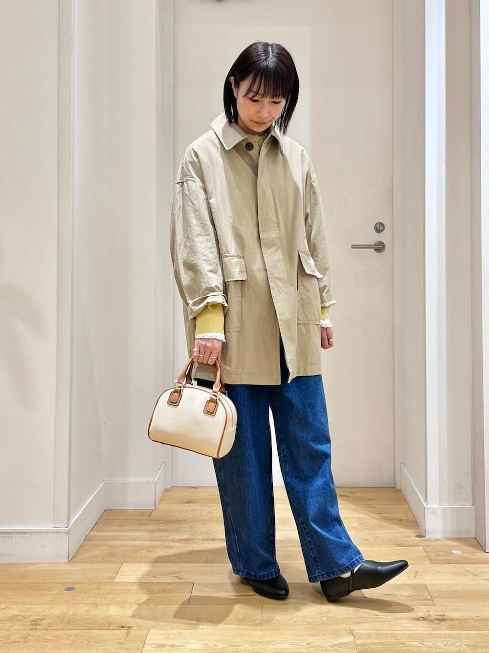 ホワイト系のシャツ/ブラウス、イエロー系のニット/セーター、ブルー系のデニムパンツを着用したレディースの冬コーディネートの4枚目の写真