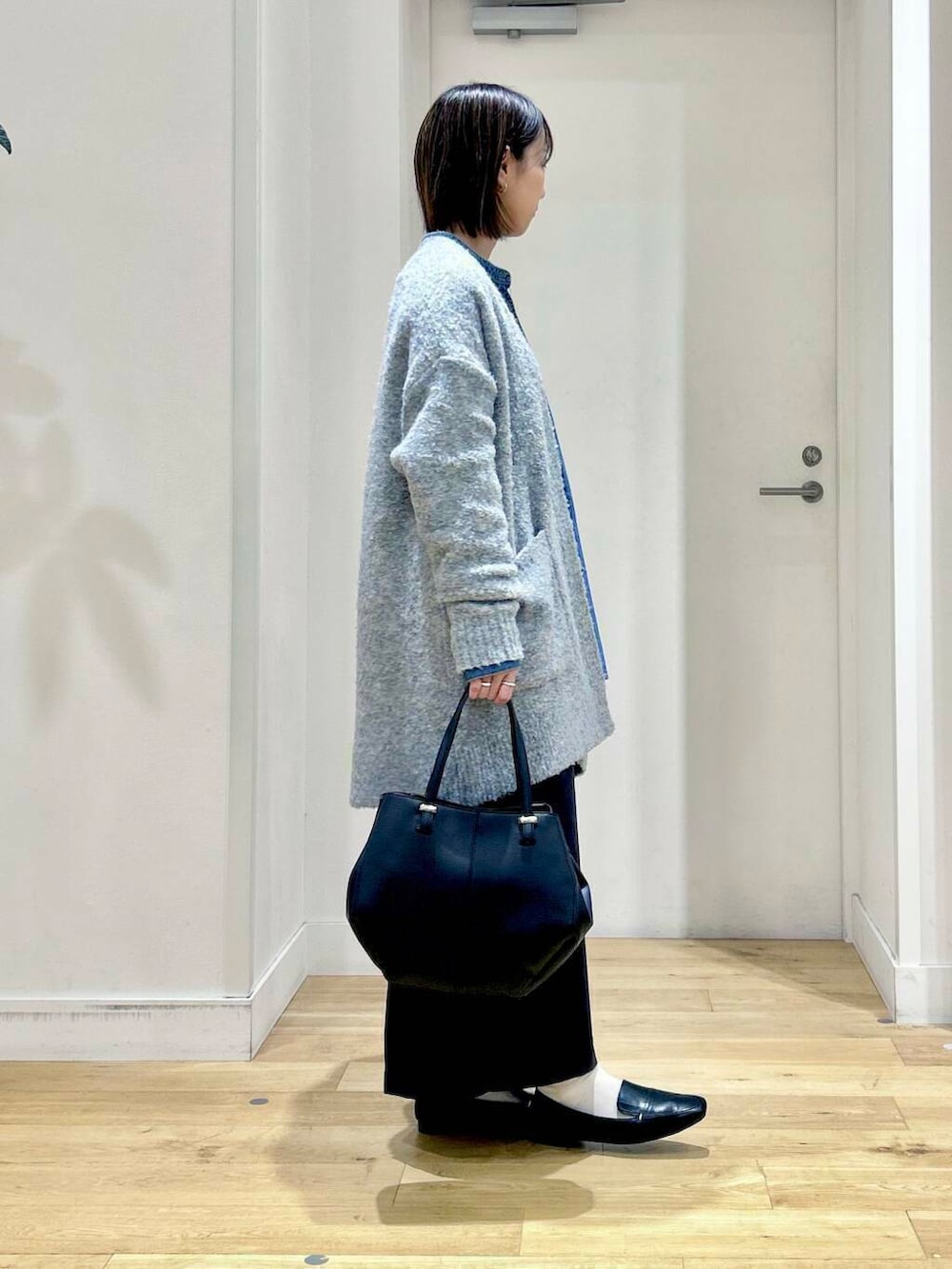 ブラック系のローファー、ブラック系のショルダーバッグ、ブルー系のスカートを着用したレディースの秋コーディネートの4枚目の写真