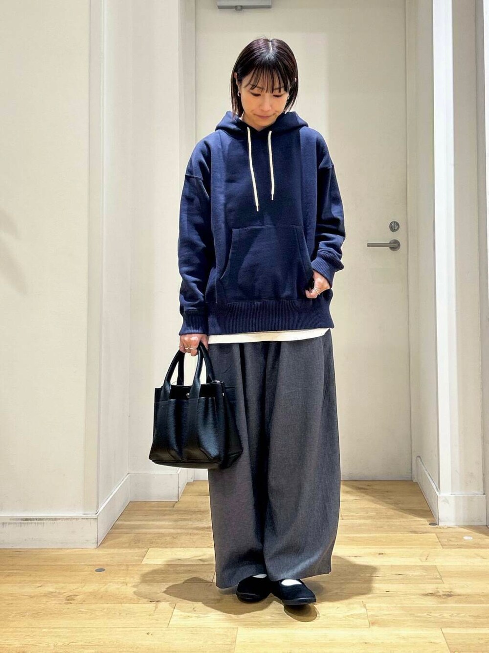 ブラック系のトートバッグ、ブラック系のバレエシューズ、ブルー系のパーカーを着用したレディースの秋コーディネートの2枚目の写真