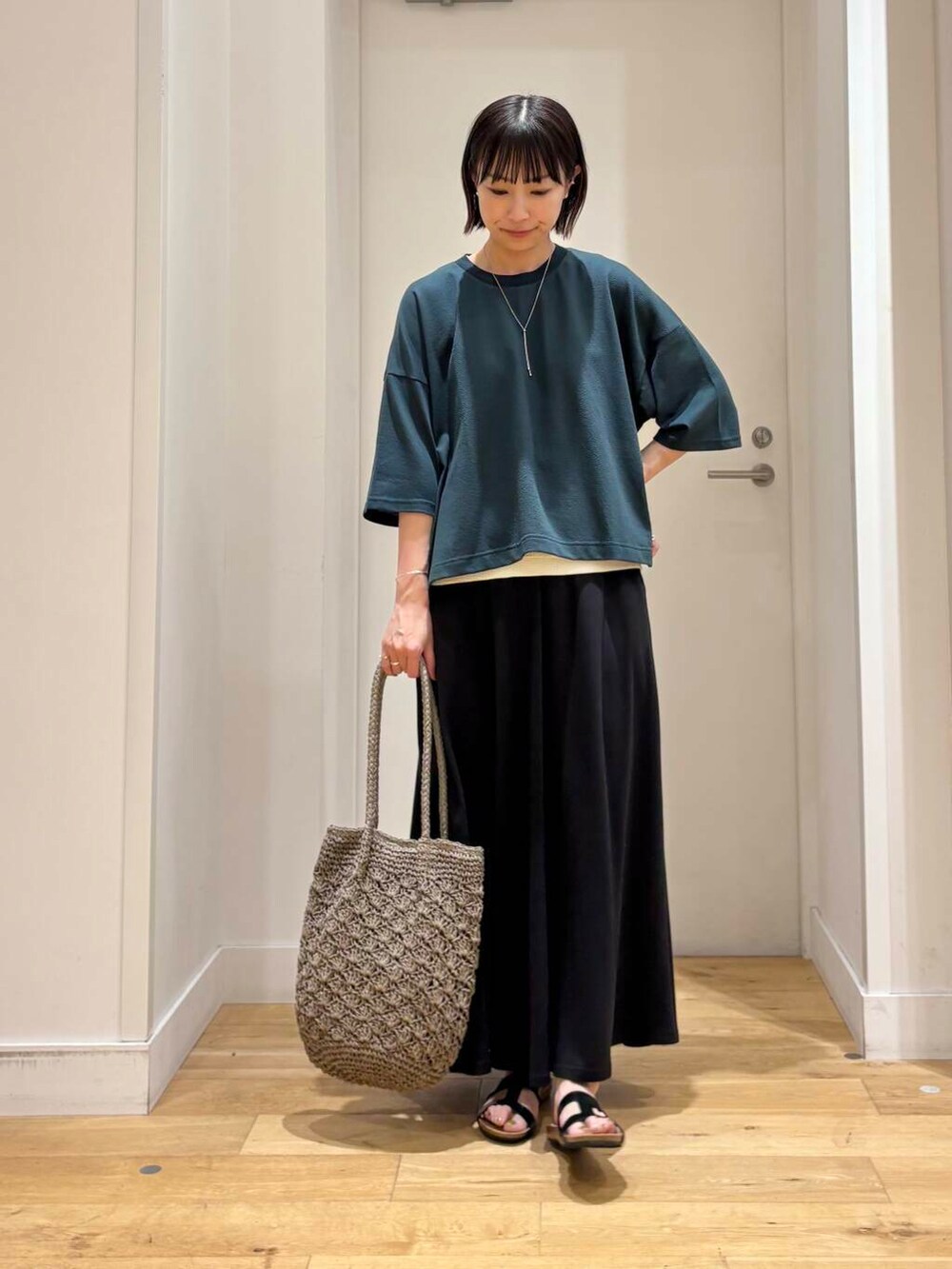 グレー系のトートバッグ、ホワイト系のタンクトップ、ブラック系のスカートを着用したレディースの夏コーディネートの2枚目の写真