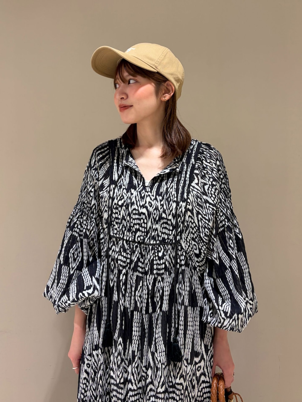 ブラック系のワンピース、ブラウン系のかごバッグ、イエロー系のサンダルを着用したレディースの夏コーディネートの4枚目の写真