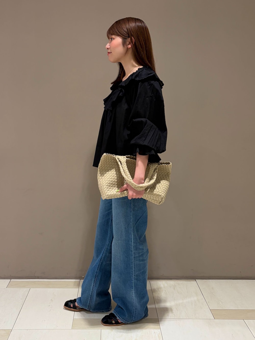ブルー系のデニムパンツ、ブラック系のシャツ/ブラウス、ベージュ系のトートバッグを着用したレディースの夏コーディネートの2枚目の写真
