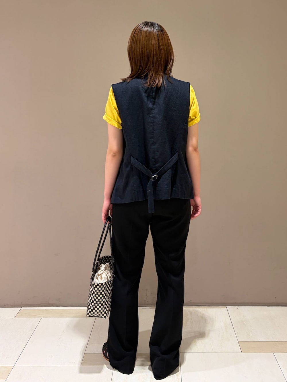 ブラック系のベスト、ブラック系のその他パンツ、イエロー系のTシャツ/カットソーを着用したレディースの春コーディネートの2枚目の写真