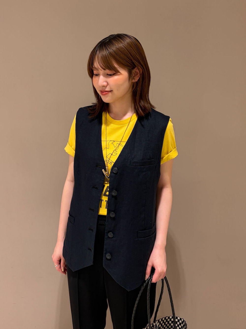 ブラック系のベスト、ブラック系のその他パンツ、イエロー系のTシャツ/カットソーを着用したレディースの春コーディネートの3枚目の写真