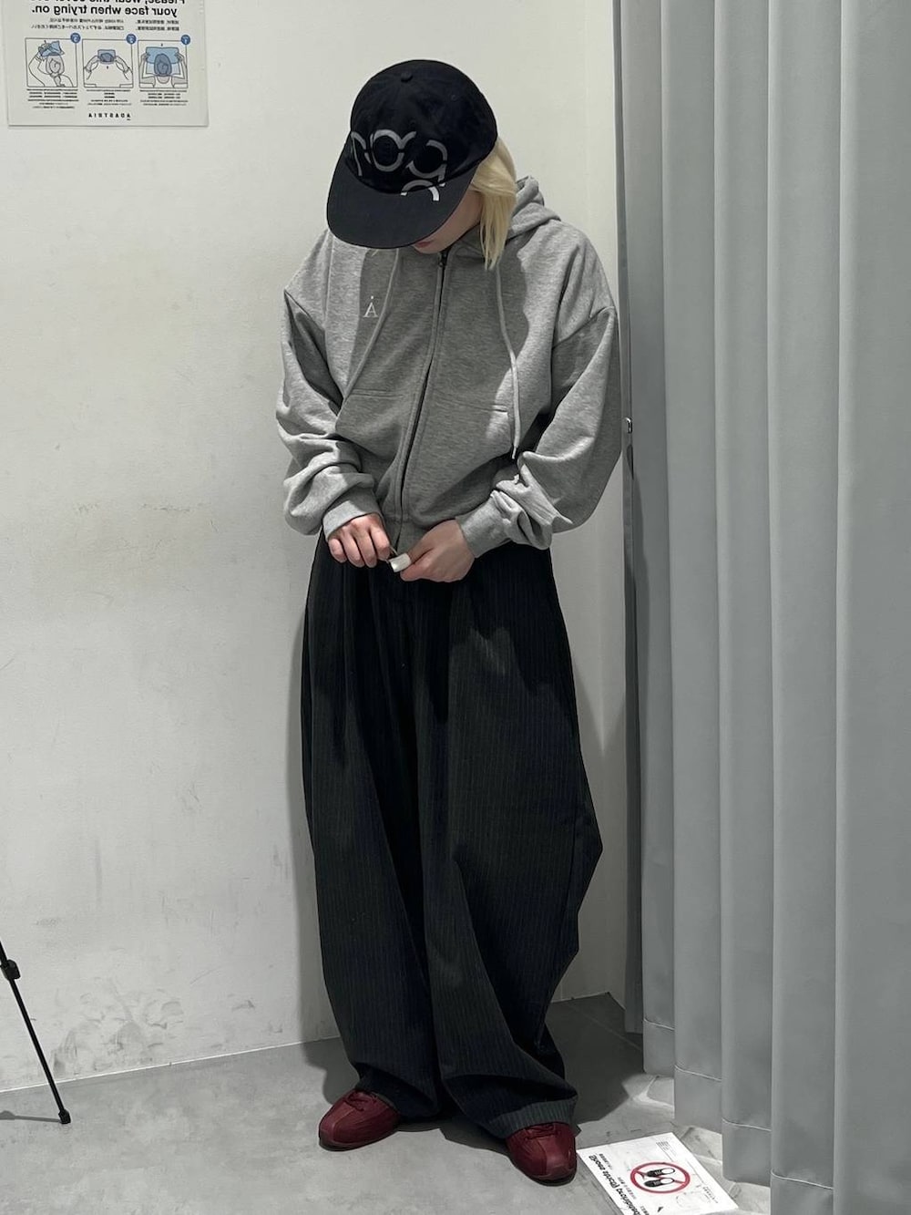 ブラック系のスラックス、グレー系のパーカー、ブラック系のキャップを着用したレディースの秋コーディネートの2枚目の写真