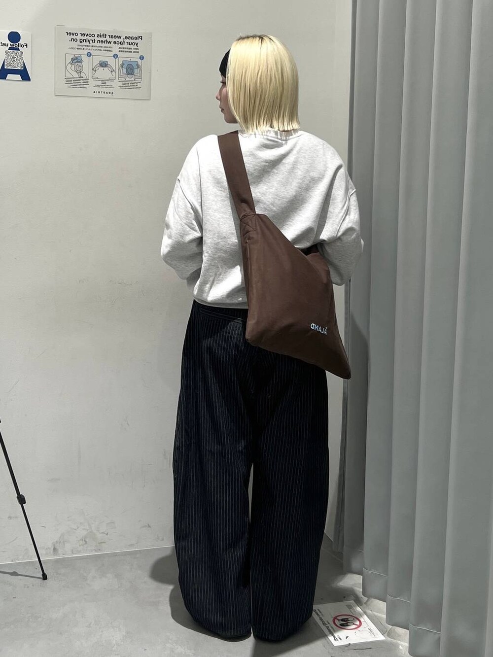 ブラウン系のトートバッグ、ブラック系のデニムパンツを着用したレディースの秋コーディネートの2枚目の写真