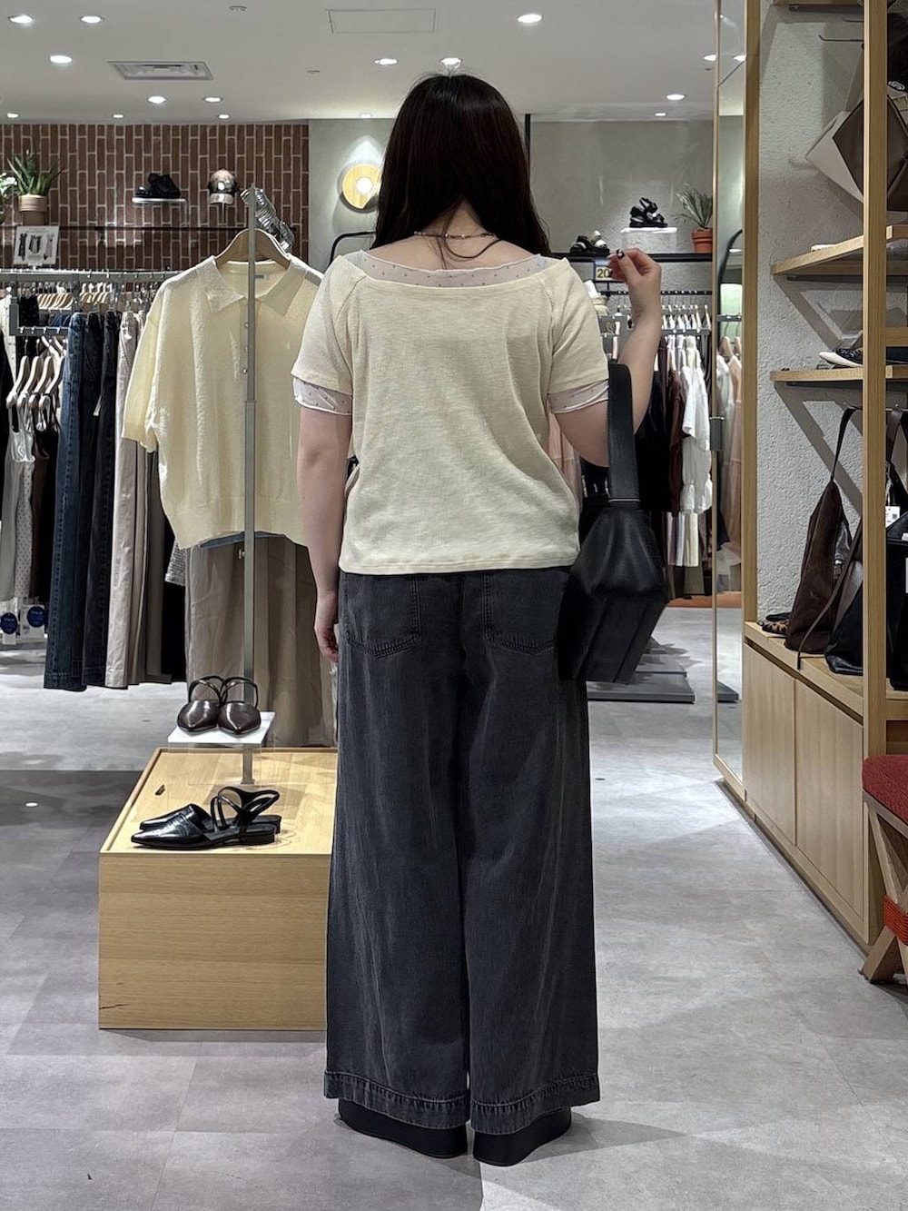 ブラック系のデニムパンツ、ブラック系のサンダル、ブラック系のショルダーバッグを着用したレディースの春コーディネートの2枚目の写真