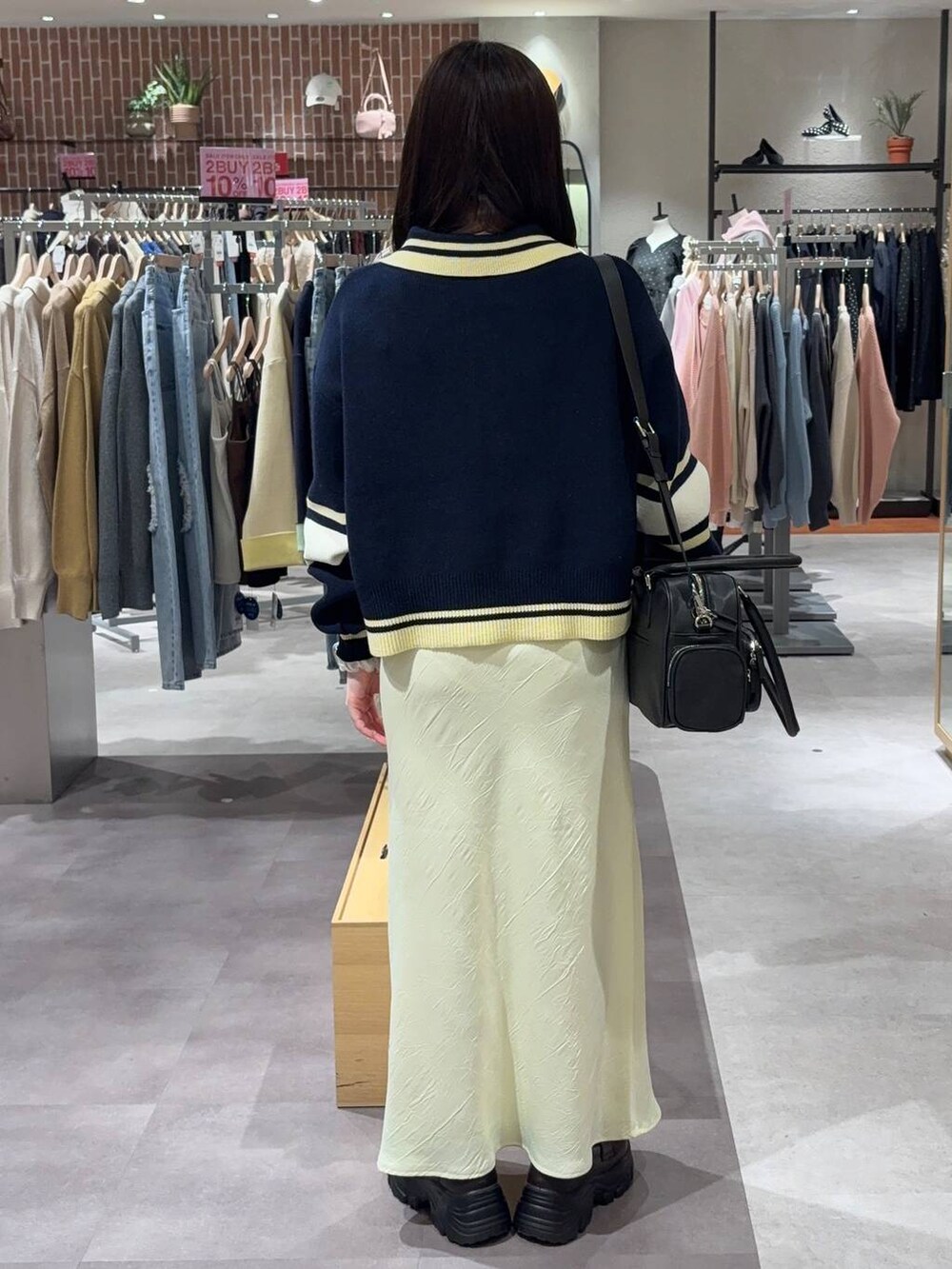 ブラック系のボストンバッグ、ブルー系のニット/セーター、シルバー系のピアス（両耳用）を着用したレディースの冬コーディネートの2枚目の写真