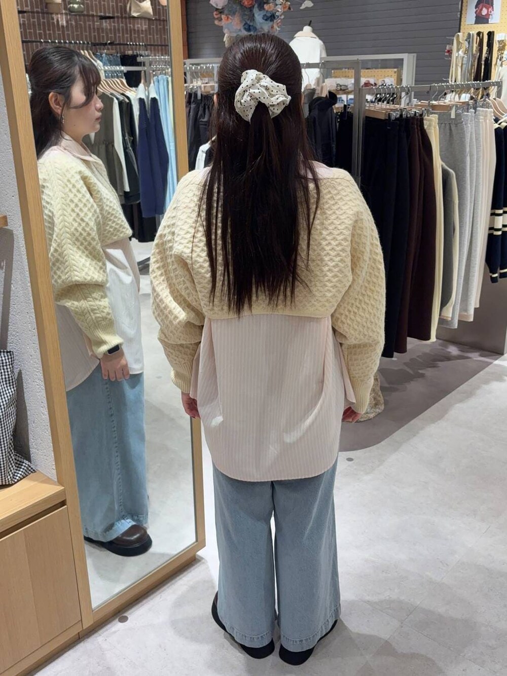 ホワイト系のニット/セーター、ブルー系のデニムパンツ、ブラウン系のショルダーバッグを着用したレディースの冬コーディネートの2枚目の写真
