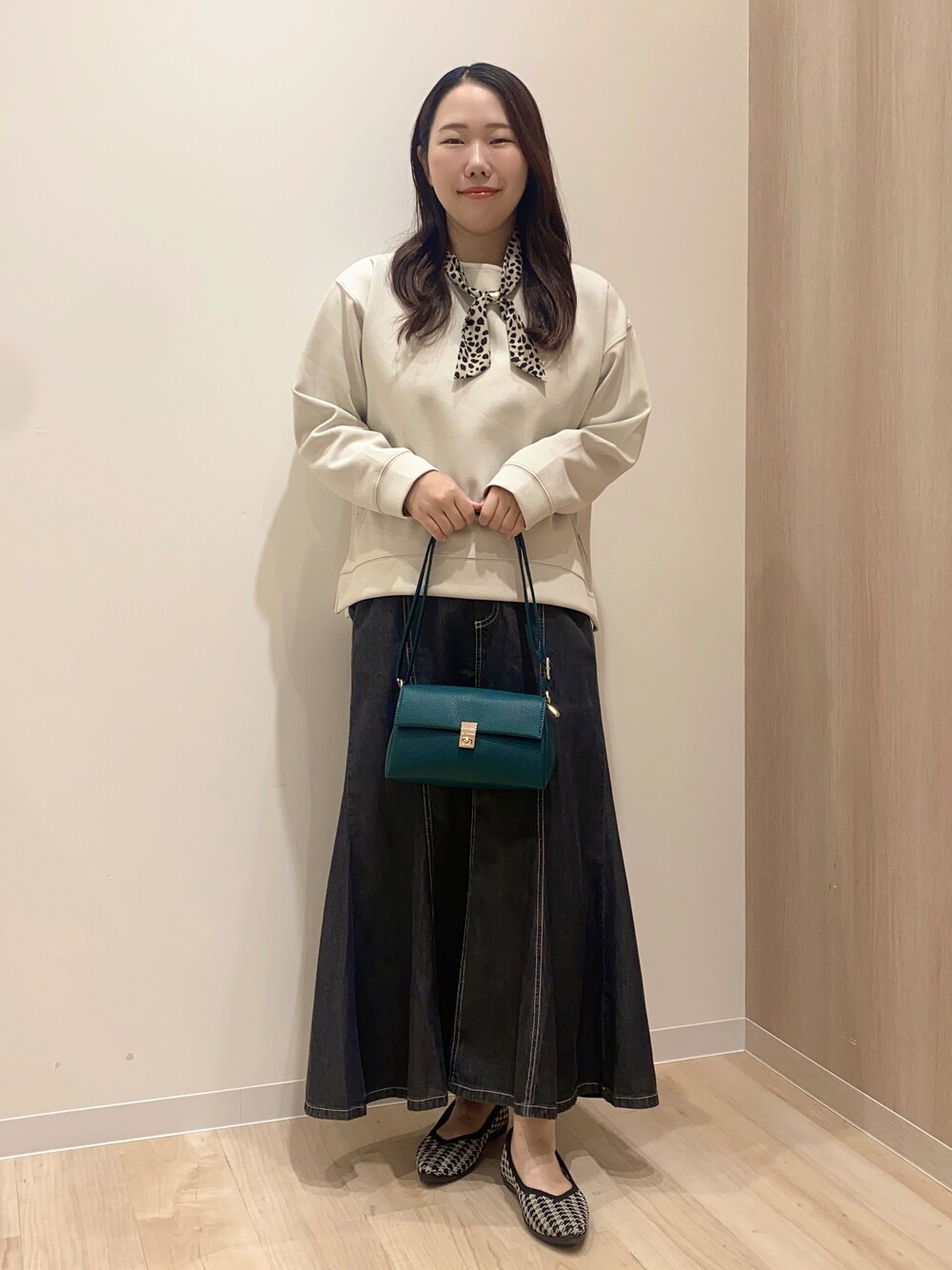 ベージュ系のTシャツ/カットソー、ブラック系のデニムスカート、グリーン系のショルダーバッグを着用したレディースの秋コーディネートの7枚目の写真