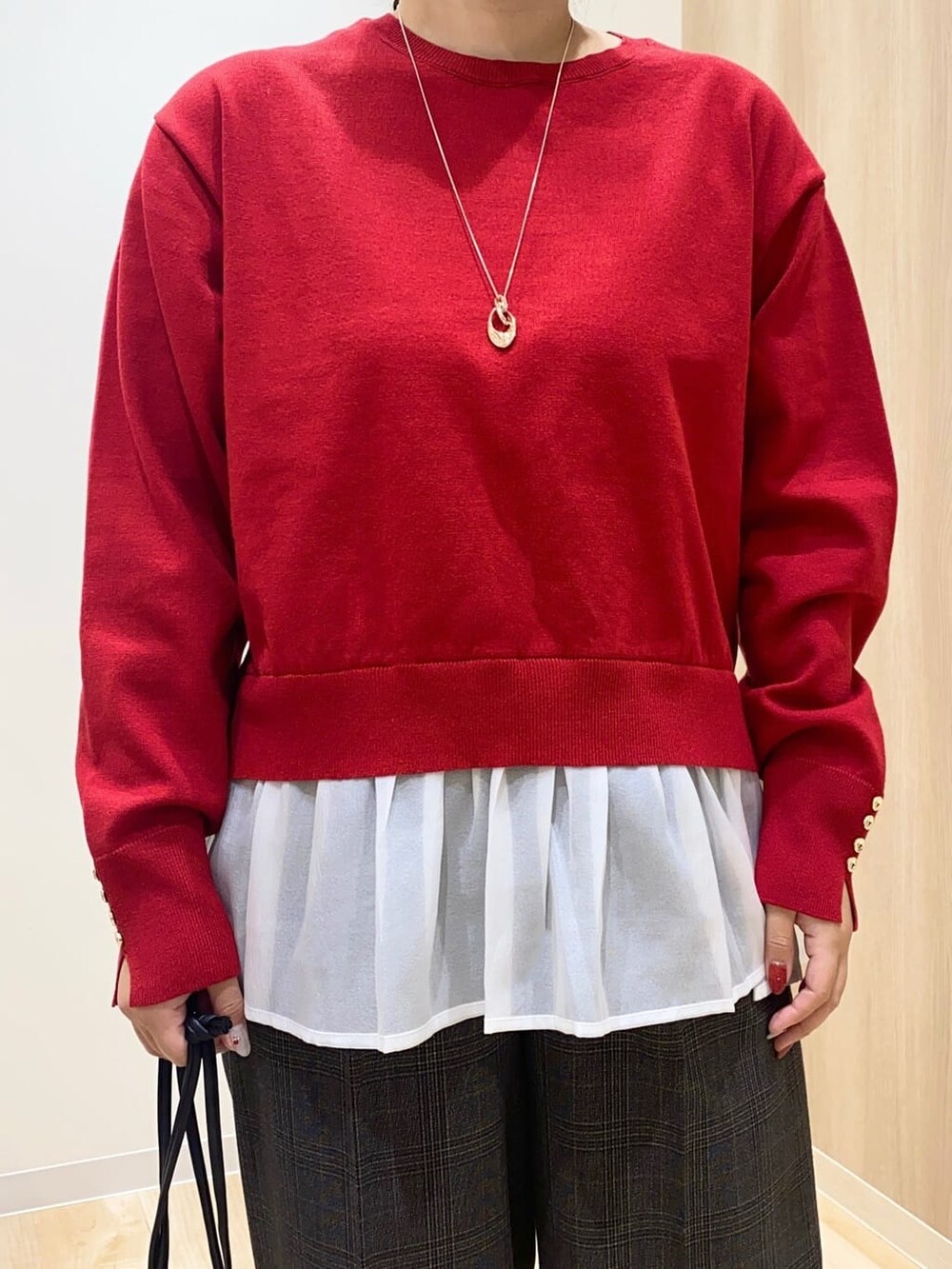 レッド系のニット/セーター、ブラック系のその他パンツ、グレー系のショルダーバッグを着用したレディースの冬コーディネートの4枚目の写真